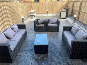 Un espacio al aire libre con mobiliario de mimbre y una mesa central.