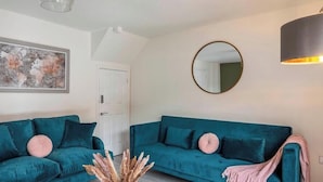 A living room with two teal sofas, a round mirror, and a floor lamp. - A Stylish, essential 3bed Home with Secure Parking (Nottingham)