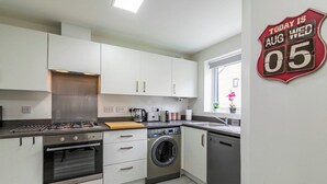 A modern kitchen with white cabinets, a gas stove, a washing machine, and a dishwasher. - A Stylish, essential 3bed Home with Secure Parking (Nottingham)