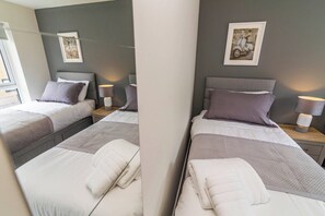 Ett hotellrum med två sängar, var och en med en kudde och ett nattduksbord med en lampa.