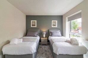 Habitación doble con dos camas, una mesita de noche con lámpara y dos cuadros en la pared.