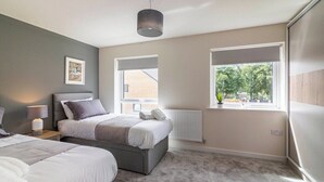 A bedroom with a bed, bedside tables, a window, and a radiator. - A Stylish, essential 3bed Home with Secure Parking (Nottingham)
