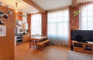 A kitchen with wooden cabinets, a dining table, chairs, and a TV.