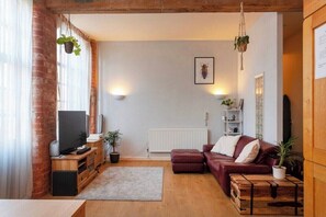A living room with a TV, wooden furniture, a red sofa, and a radiator.