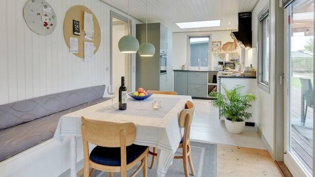 Une cuisine moderne avec un coin repas, une grande fenêtre et une plante en pot.