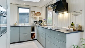 Une cuisine moderne avec des meubles de couleur bleu clair, une hotte noire et une fenêtre qui laisse entrer la lumière naturelle.