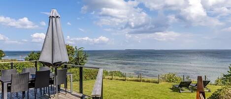 A deck with outdoor furniture overlooking a body of water.