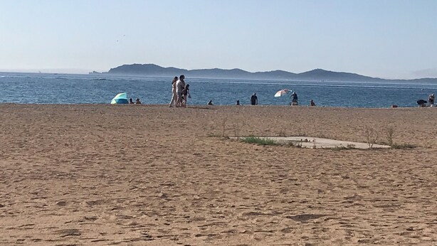 A beach with people walking and sitting, a clear sky, and distant mountains. - Villa sur la Mer, Refaite à Neuve en Juillet 2023 (Hyères)
