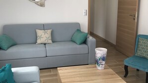 A living room with a grey sofa, teal cushions, a wooden coffee table, and a starfish-shaped mirror on the wall. - Villa sur la Mer, Refaite à Neuve en Juillet 2023 (Hyères)