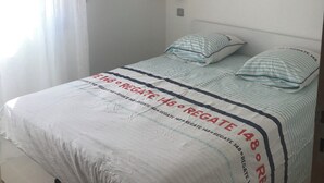 A bedroom with a bed, a hanging light fixture, and a window with curtains. - Villa sur la Mer, Refaite à Neuve en Juillet 2023 (Hyères)