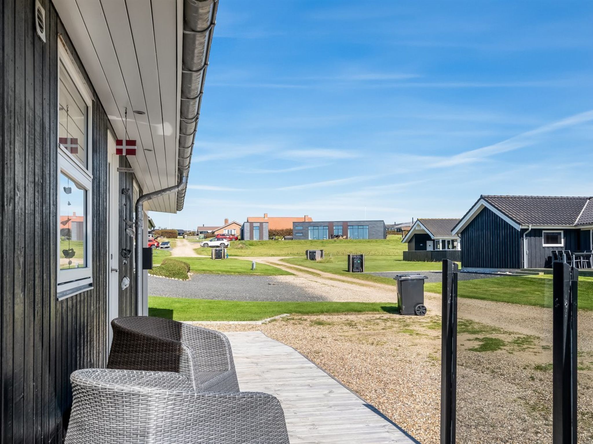A modern building with a covered outdoor seating area and a view of the surrounding landscape.