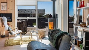 Un salon chaleureux avec une cheminée, des sièges confortables et une vue sur l’extérieur.