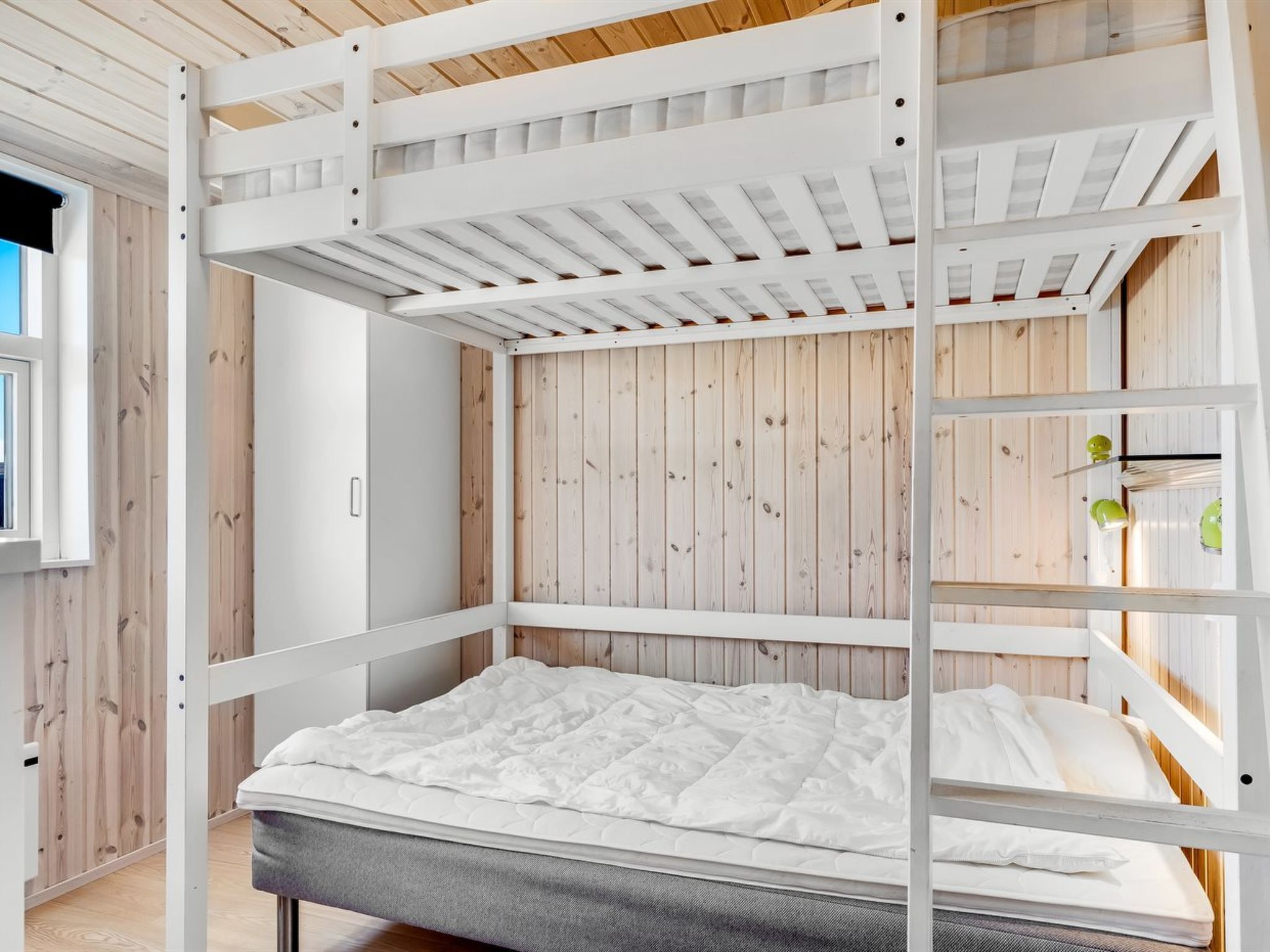 Ein Etagenbett mit Holzkopfteil und weißer Matratze.