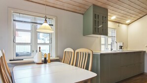 Eine kleine Küche mit Essbereich, Holzboden und einem Fenster mit Jalousien.