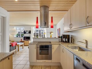 Una cocina moderna con una isla central, electrodomésticos de acero inoxidable y un comedor con mantel rojo.