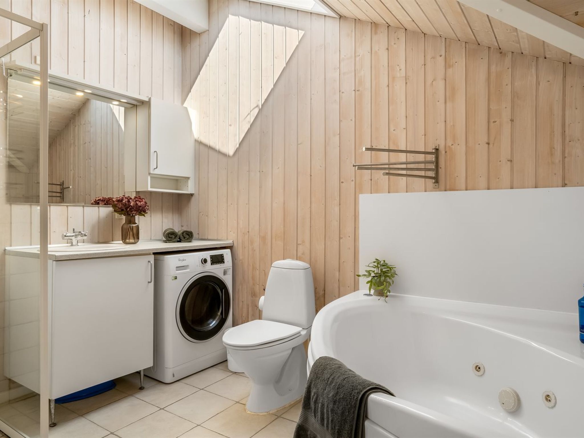 Et moderne badeværelse med vaskemaskine, toilet og badekar.