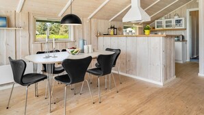 Une cuisine moderne dotée d’un îlot central, d’un plafond en bois et offrant une vue sur la verdure environnante.