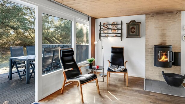 Una sala de estar moderna con chimenea, suelo de madera y vistas al exterior.