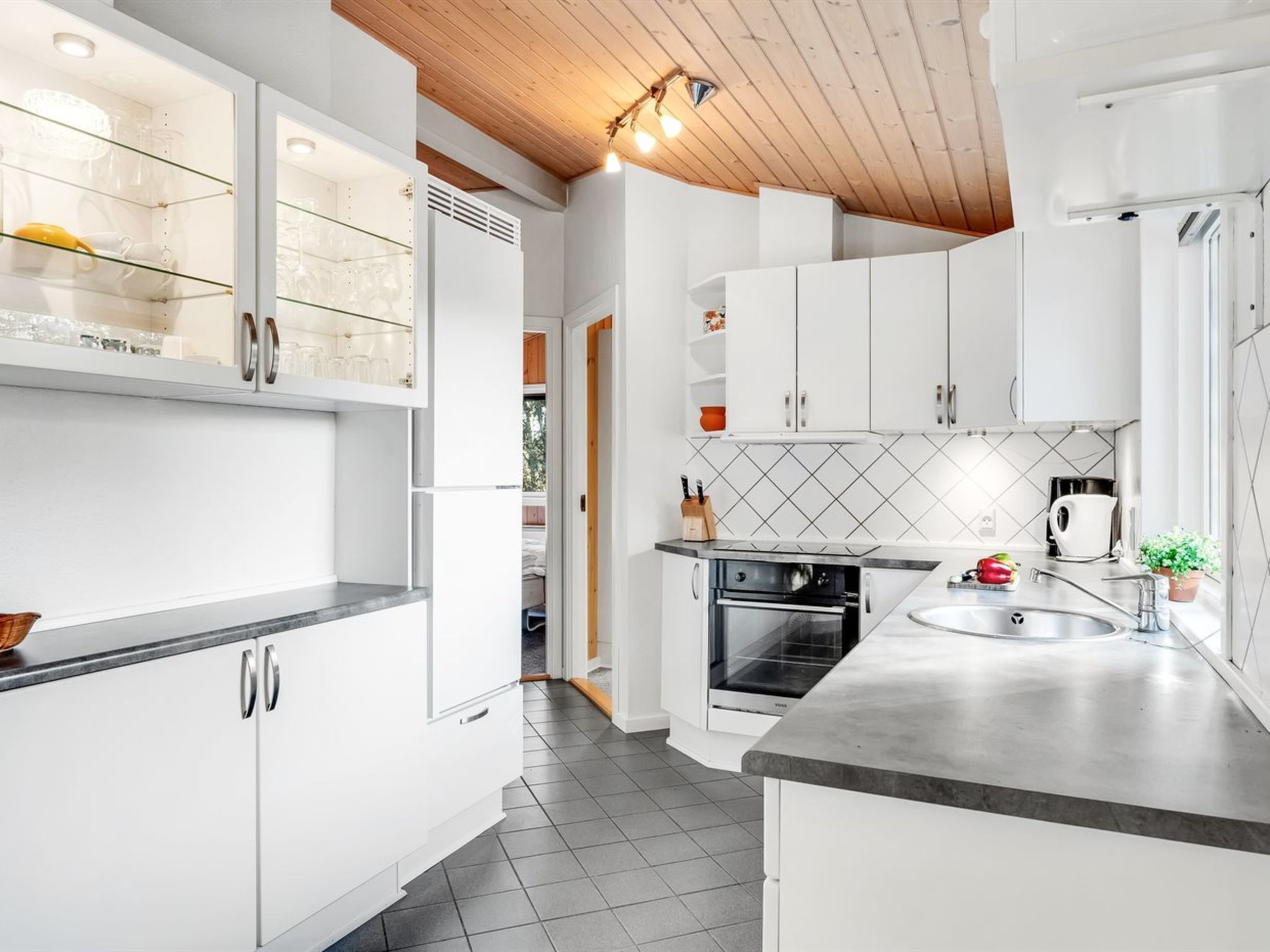 Una cocina moderna con armarios blancos, horno integrado y salpicadero de azulejos.