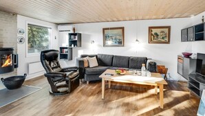 Una sala de estar acogedora con chimenea, un sofá, una mesa de comedor y un sillón de cuero negro.