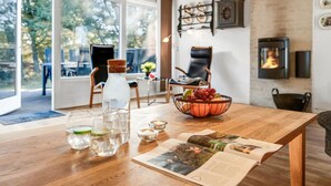 Una sala de estar moderna con una mesa de madera, una chimenea y un ventanal con vistas a un jardín.