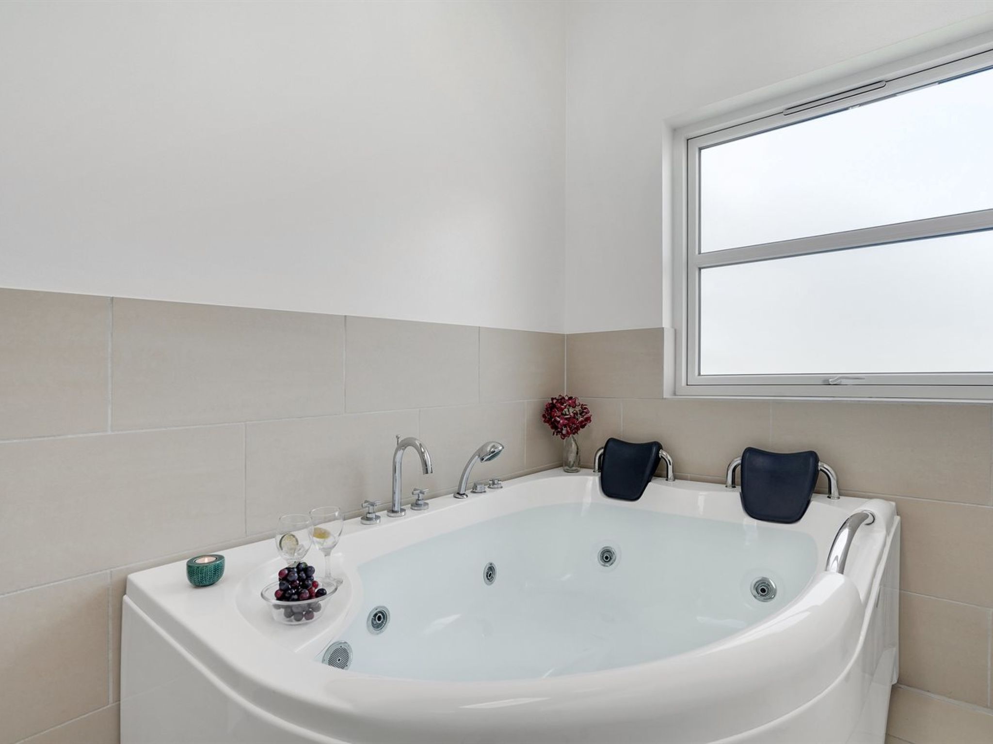A modern bathroom with a freestanding bathtub, a small sink, and a window providing natural light.