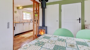 Ett mysigt rum med ett vadderat sängöverkast, en vedeldad kamin, en dörr och utsikt över ett köksområde.