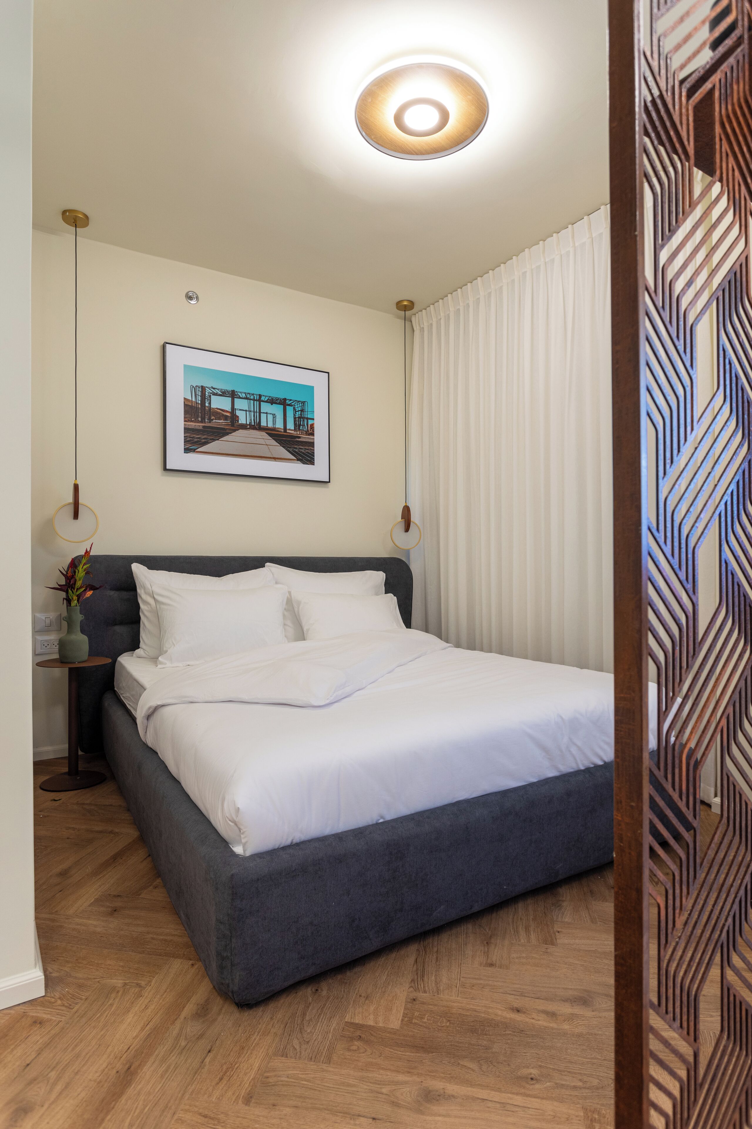 Een moderne hotelkamer met een groot bed, een ingelijste foto aan de muur en een houten vloer.