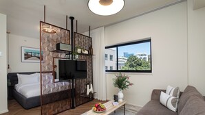 Uma sala de estar moderna com um sofá, uma mesa de centro com frutas, uma televisão e um divisório decorativo.