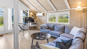 Ein modernes Wohnzimmer mit einer Eckcouch, einem runden Couchtisch, einem Fernseher und einem Balkon mit Blick.
