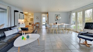Un soggiorno moderno con divano, tavolino e zona pranzo con sedie.