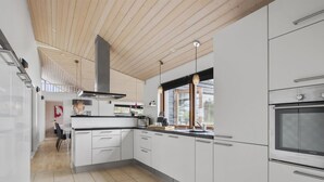 Eine moderne Küche mit weißen Schränken, einem Einbauofen und einem großen Fenster, das für natürliches Licht sorgt.