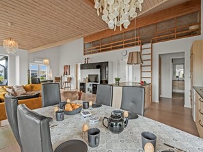 Moderni olohuone, jossa on ruokailutila, keittiö ja avoin pohjaratkaisu.