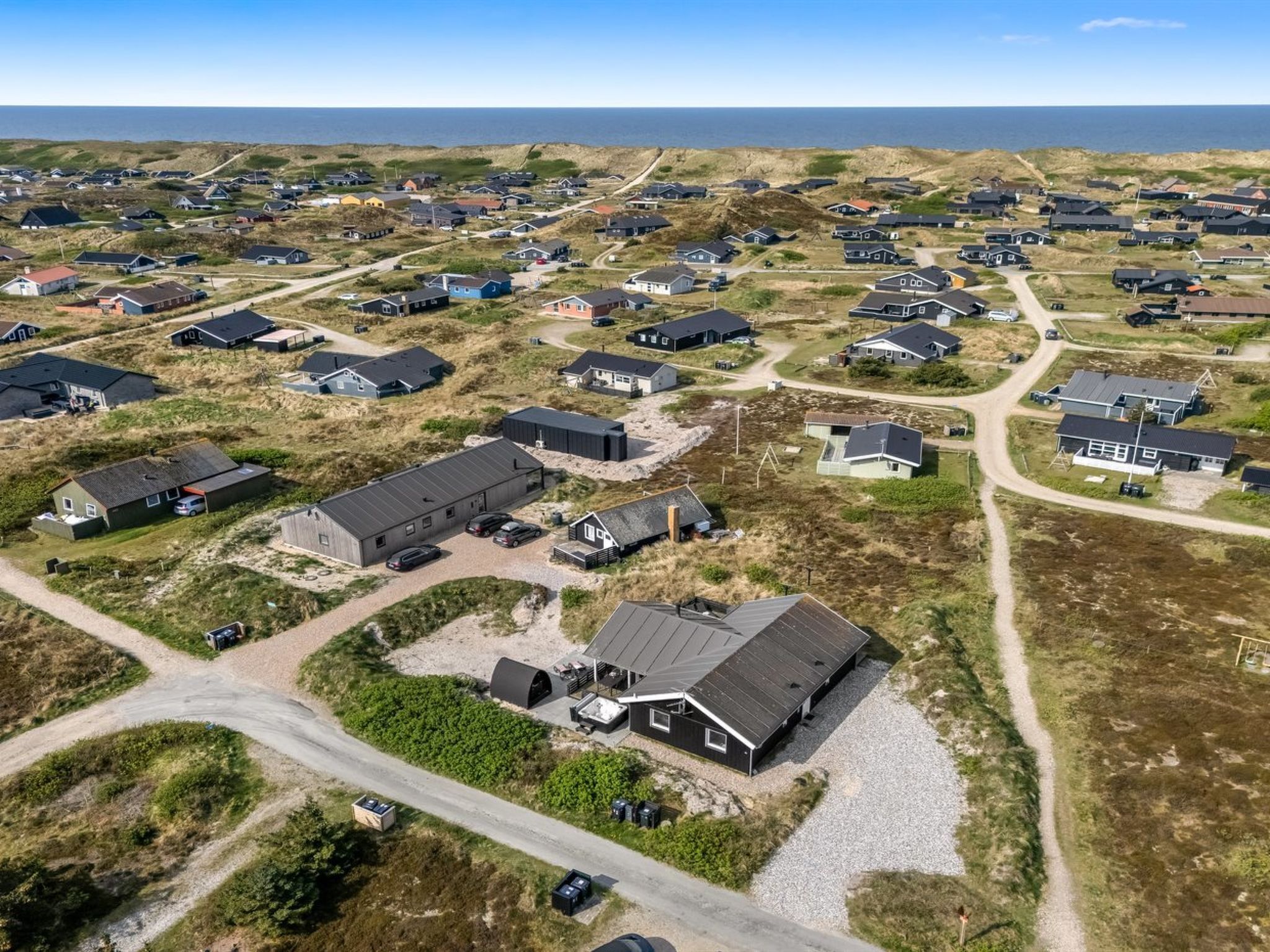 An aerial view of a residential area with houses, roads, and a beach in the background.