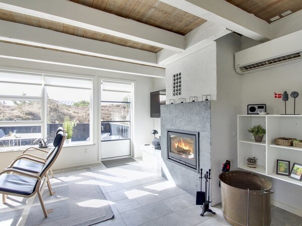 Een moderne woonkamer met een open haard, grote ramen en uitzicht op het buitenleven.