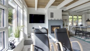 A modern living room with a fireplace, two black leather chairs, a television, and a dining area with a table and chairs. - "Grita" - 500m from the sea by Interhome (Vejers Strand)