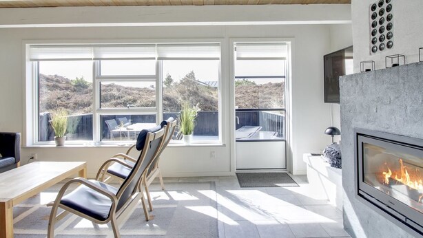 A modern living room with a fireplace, large windows, and a view of the outdoors. - "Grita" - 500m from the sea by Interhome (Vejers Strand)