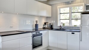 A modern kitchen with white cabinetry, a built-in oven, a coffee maker, and a window providing natural light. - "Grita" - 500m from the sea by Interhome (Vejers Strand)