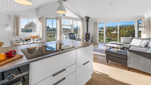 Una cocina moderna con una isla central, un comedor con vistas y un rincón de descanso acogedor con chimenea.