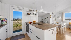 Una cocina moderna con armarios blancos, una isla grande e iluminación colgante.