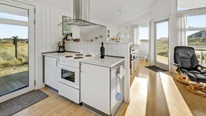 Cocina moderna con una isla central, estufa y un amplio ventanal con vistas a un paisaje natural.