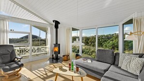 Un salón amplio con un ventanal grande, una chimenea, un sofá y un sillón.