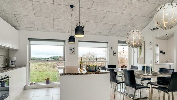 Une cuisine moderne dotée de grandes fenêtres, d’un îlot central et d’un éclairage contemporain.
