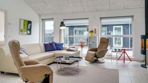 Un salon moderne avec un canapé beige, deux fauteuils inclinables, une table basse et une cheminée.