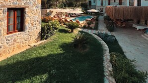 A stone building with a pool, outdoor seating, and a thatched-roof structure. - Dilek Hanım Konağı Datça (Datça)