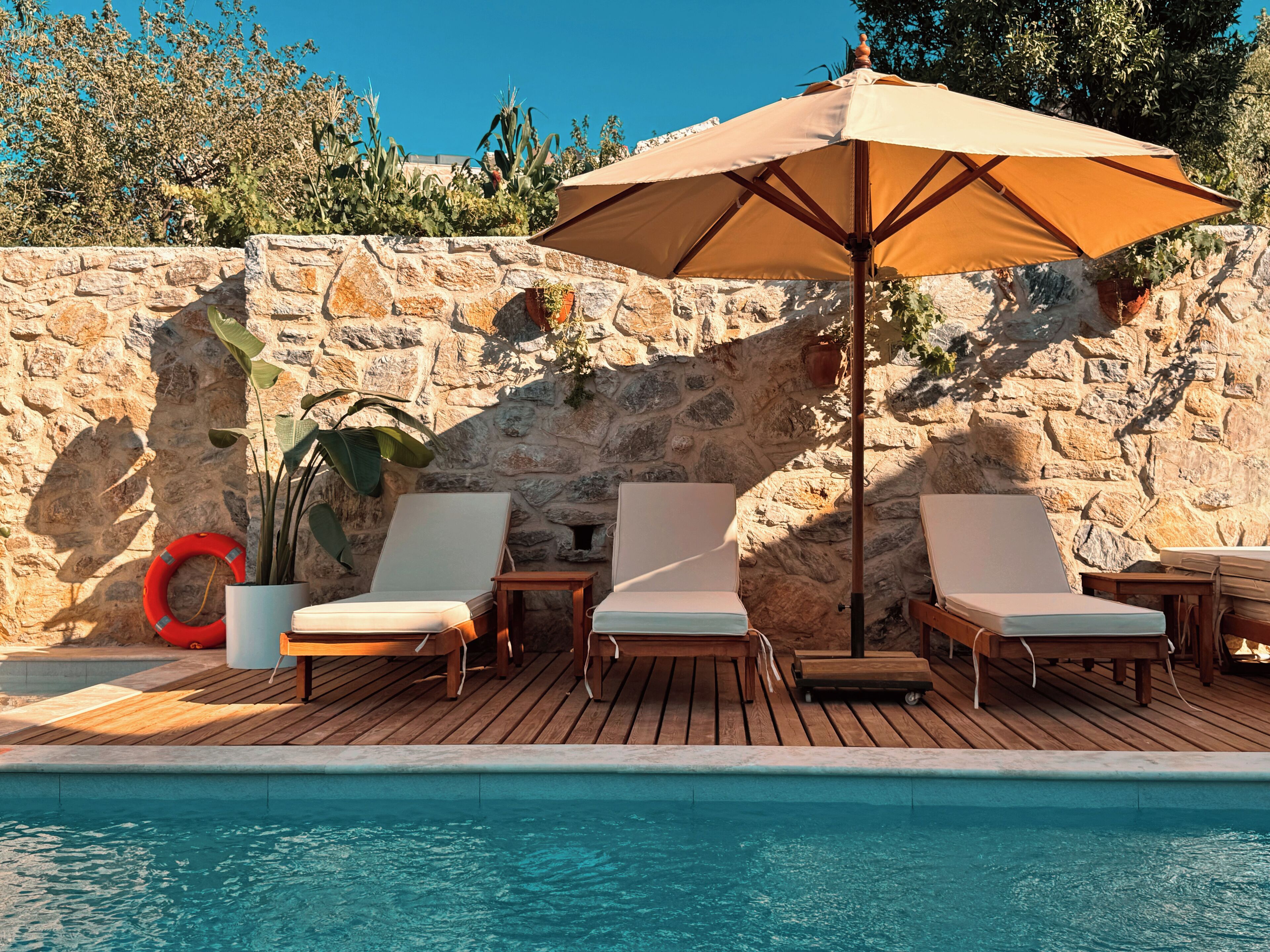 A poolside area with lounge chairs and a large umbrella.