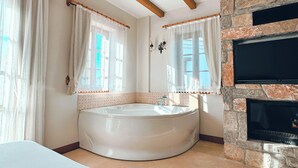 A spacious bathroom with a large bathtub, wooden beams on the ceiling, and a stone fireplace. - Dilek Hanım Konağı Datça (Datça)
