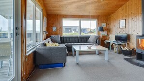 Een gezellige woonkamer met een bank, bijzettafeltje en een open haard.