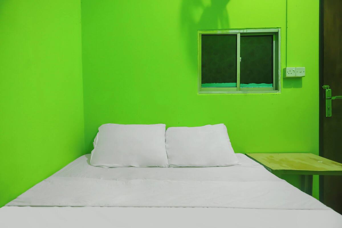 Una habitación con una cama, una mesita y un ventanal.