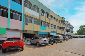A multi-story building with parked cars and motorcycles on the ground floor. - Hotel O Budi Homestay SyariahNearGrand Batam Mall (Batam)